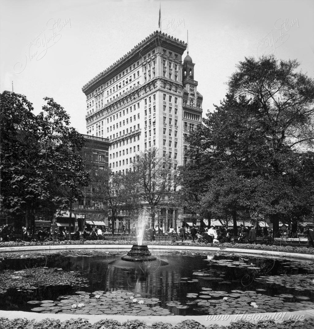 A close-up view of the Union Square Fountain with the Metropolitan Building in the background.