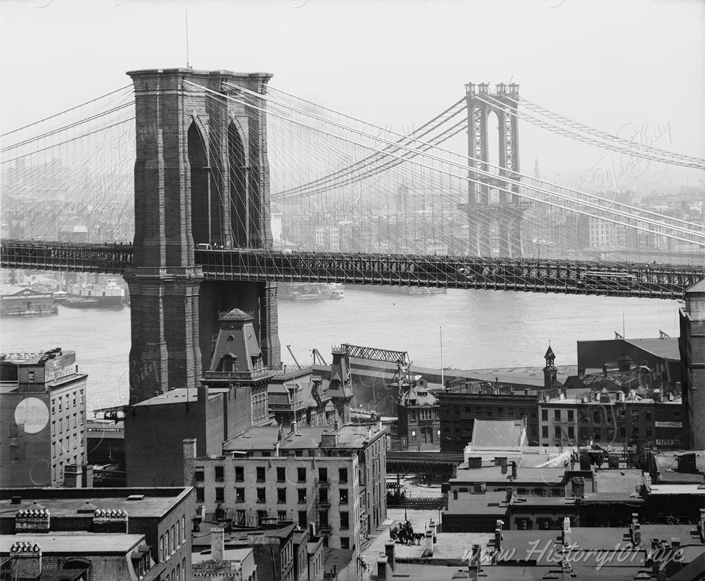 An iconic view of the both East River bridges with downtown Manhattan in the background and plenty of traffic in the East River.