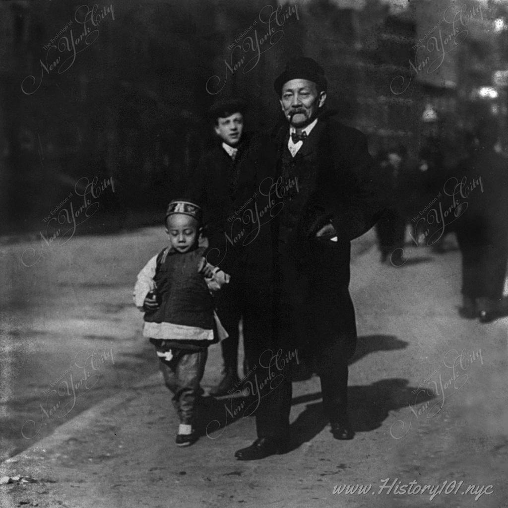 A Chinese-American man walking with son on the street in NYC's Chinatown district.
