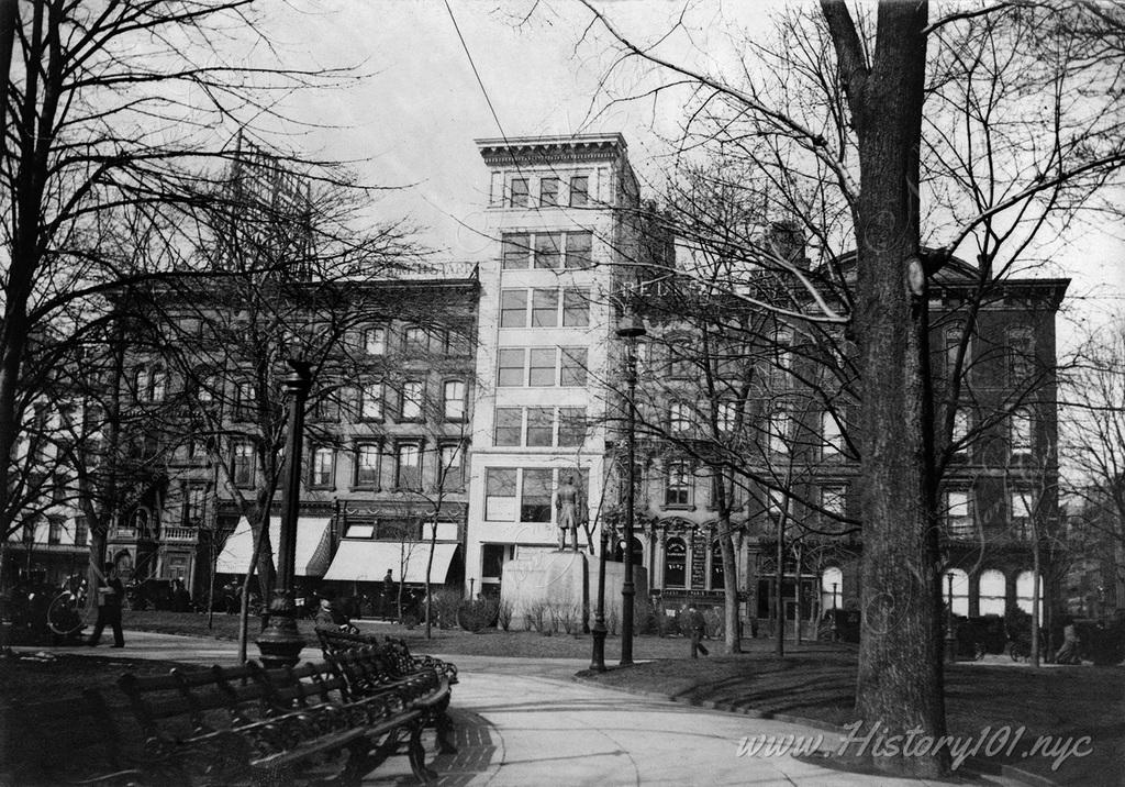 Photograph of a row of buildings and storefronts taken from the perspective of Madison Square Park.