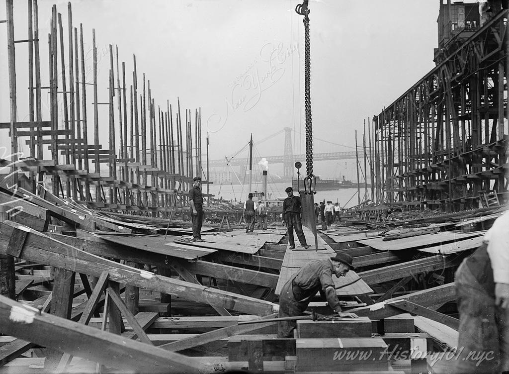 Photograph of construction workers at the Brooklyn Navy Yard building a large timber framed ship from the keel up.