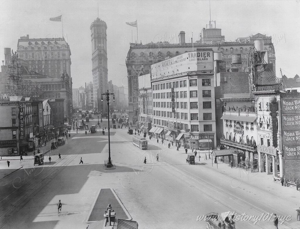 Photograph shows Longacre Square, now named Times Square, with theaters, shops, hotels, and the Times Building.
