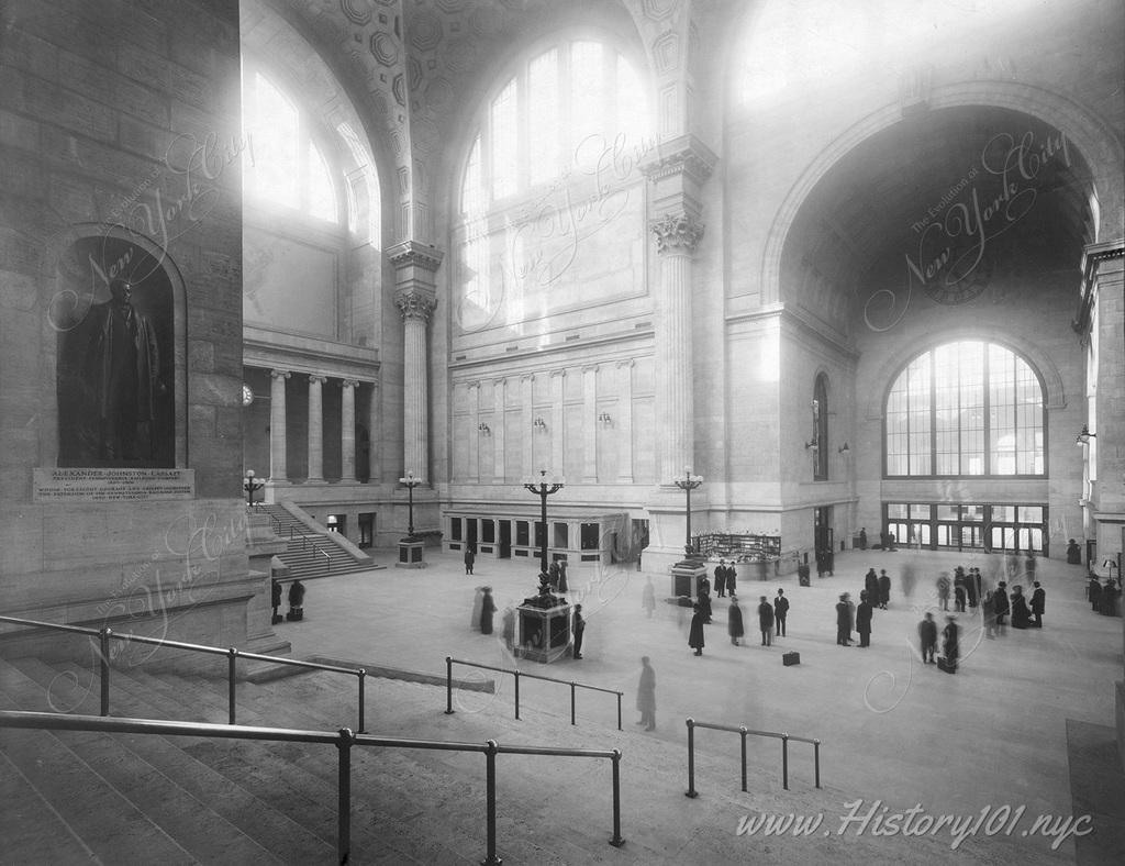 Passengers in the waiting room at Pennsylvania Station, with statue of Alexander Johnston Cassatt, president of the Pennsylvania Railroad Company.