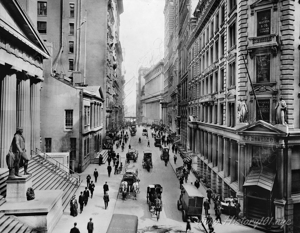 Photograph of pedestrians and horse drawn carriages on Wall Street looking, east from Nassau Street.