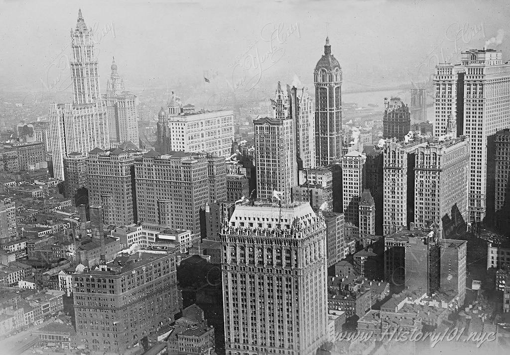 A bird's eye view of Manhattan's famous skyline, including the Singer Building and the newly completed Woolworth Building.