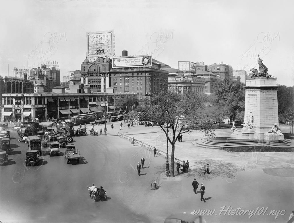 A photograph of cars and pedestrians making their way around Columbus Circle looking north.