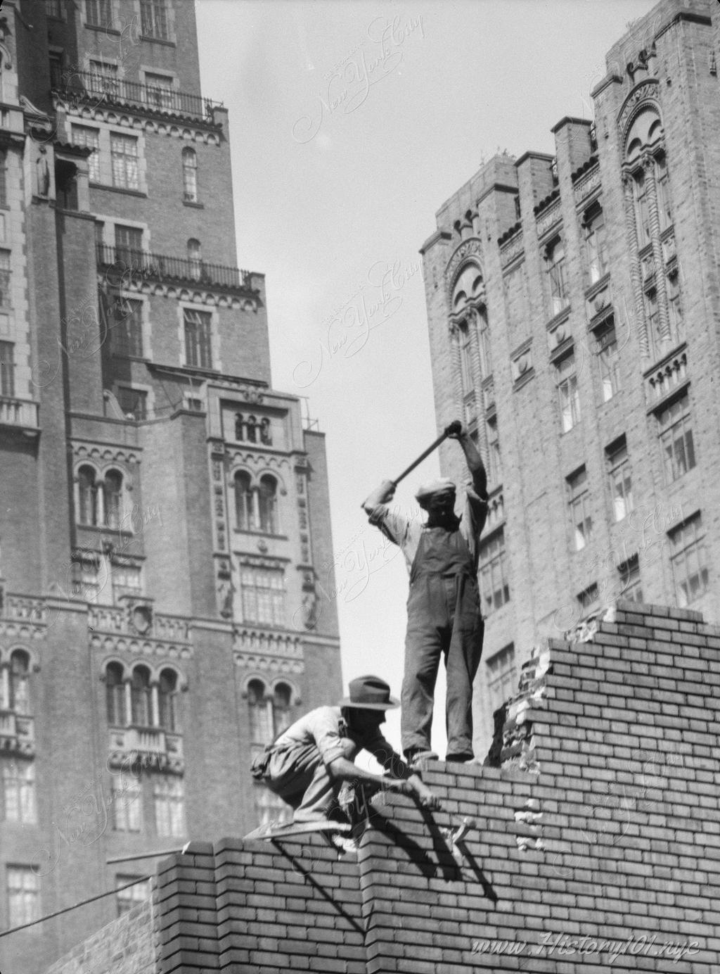 Photograph of a pair of construction workers demolishing a wall.