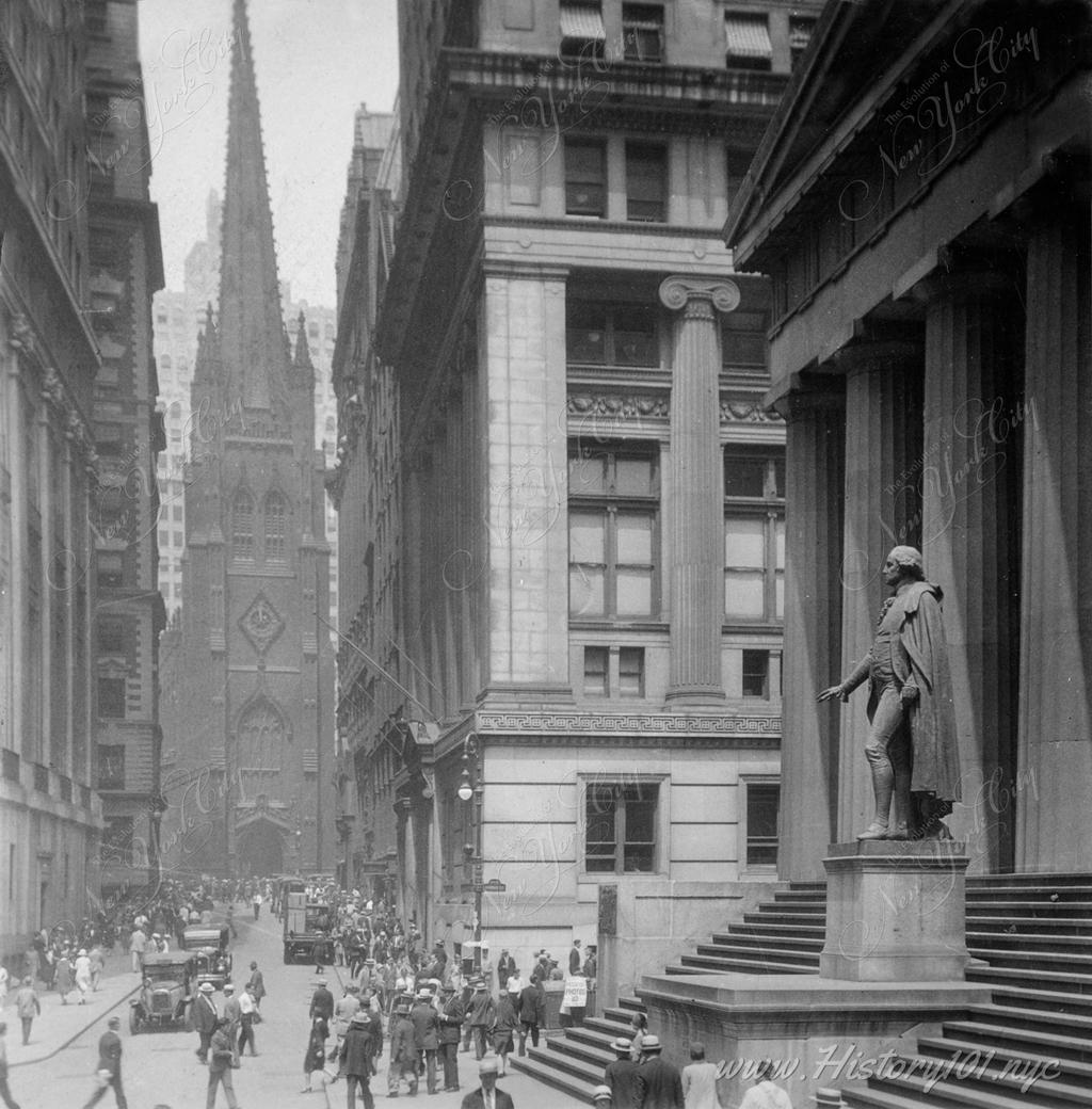 Photograph of pedestrians on Wall Street with Trinity Church in the background.