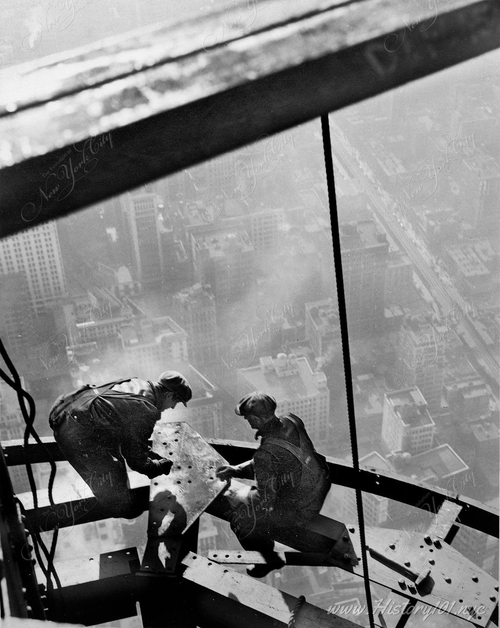 Photograph of two construction workers, perched atop the steel framework of the Empire State Building.