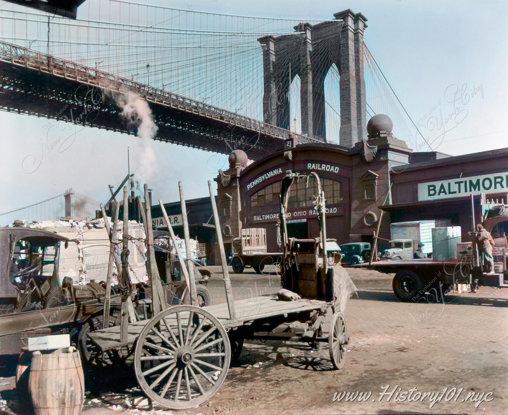 Photograph of trucks and wagons parked on Pier 21 at the Brooklyn Bridge on the Manhattan side.
