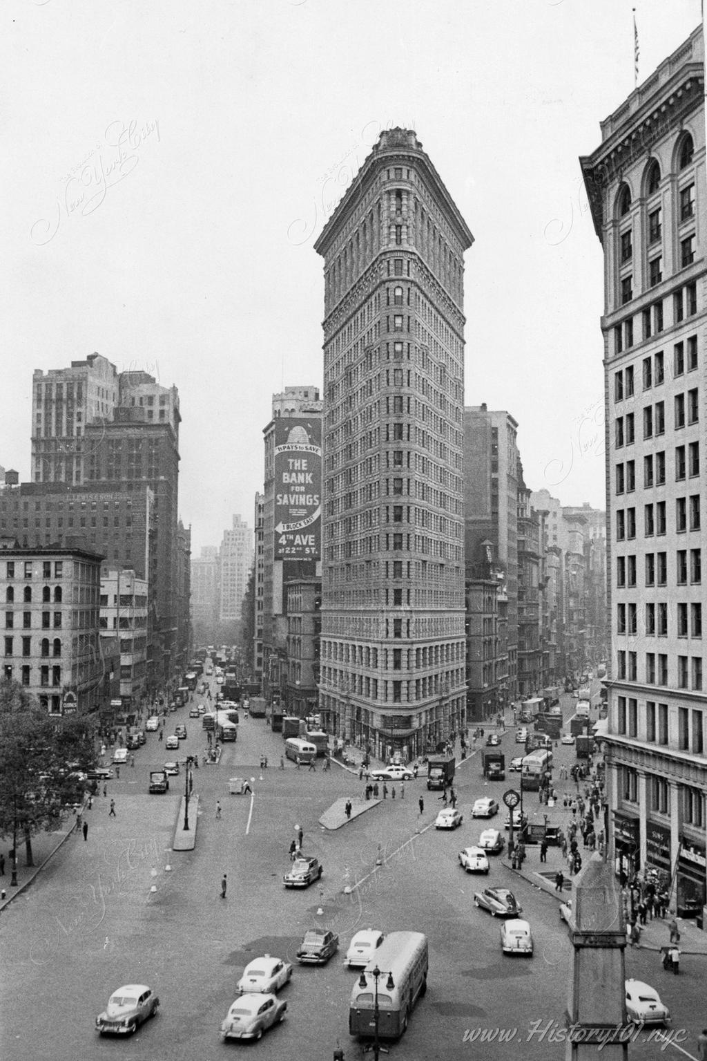 Elevated perspective of The Flatiron building and the busy intersection of 5th Avenue and Broadway.