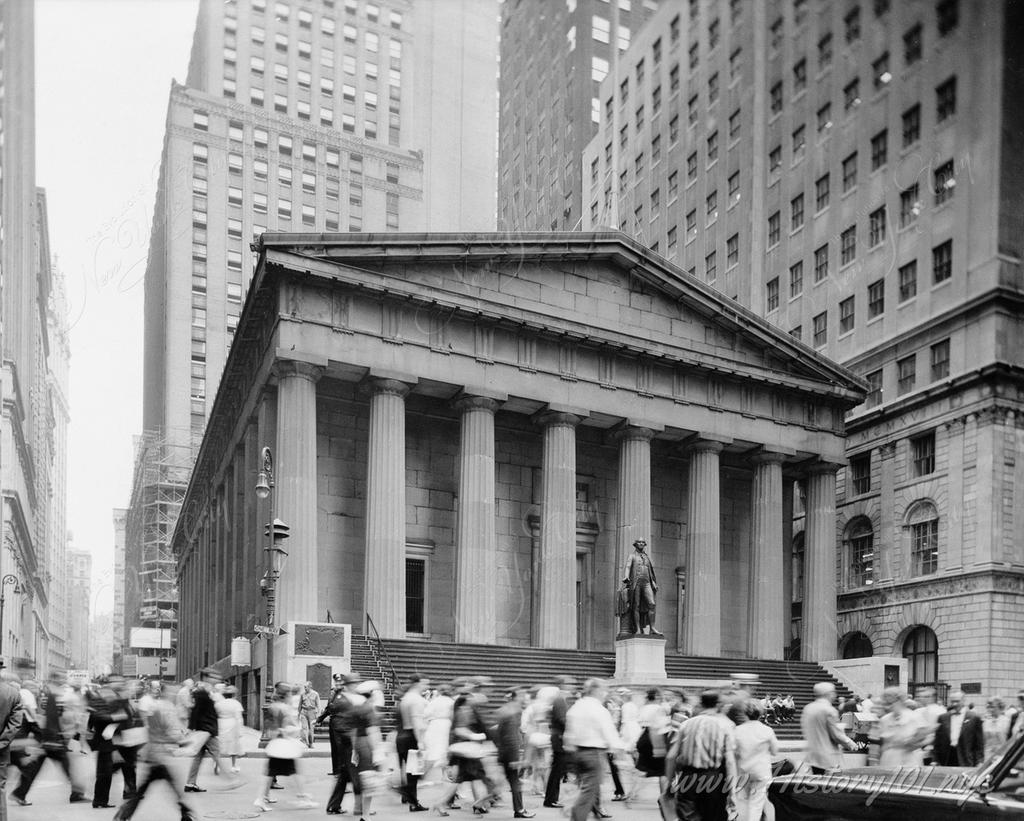 Pedestrians crowd the intersection of Main And Nassau Streets at U. S. Custom House on 28 Wall Street in Downtown Manhattan.