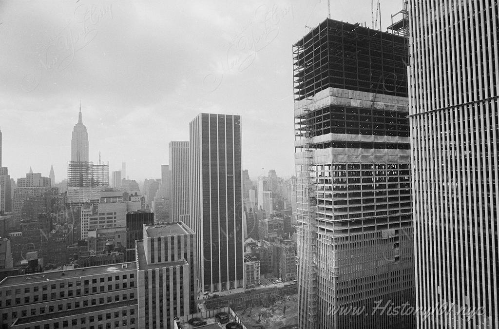 Elevated perspective of the McGraw Hill Building construction. The Empire State Building and midtown skyline are visible in the distance.