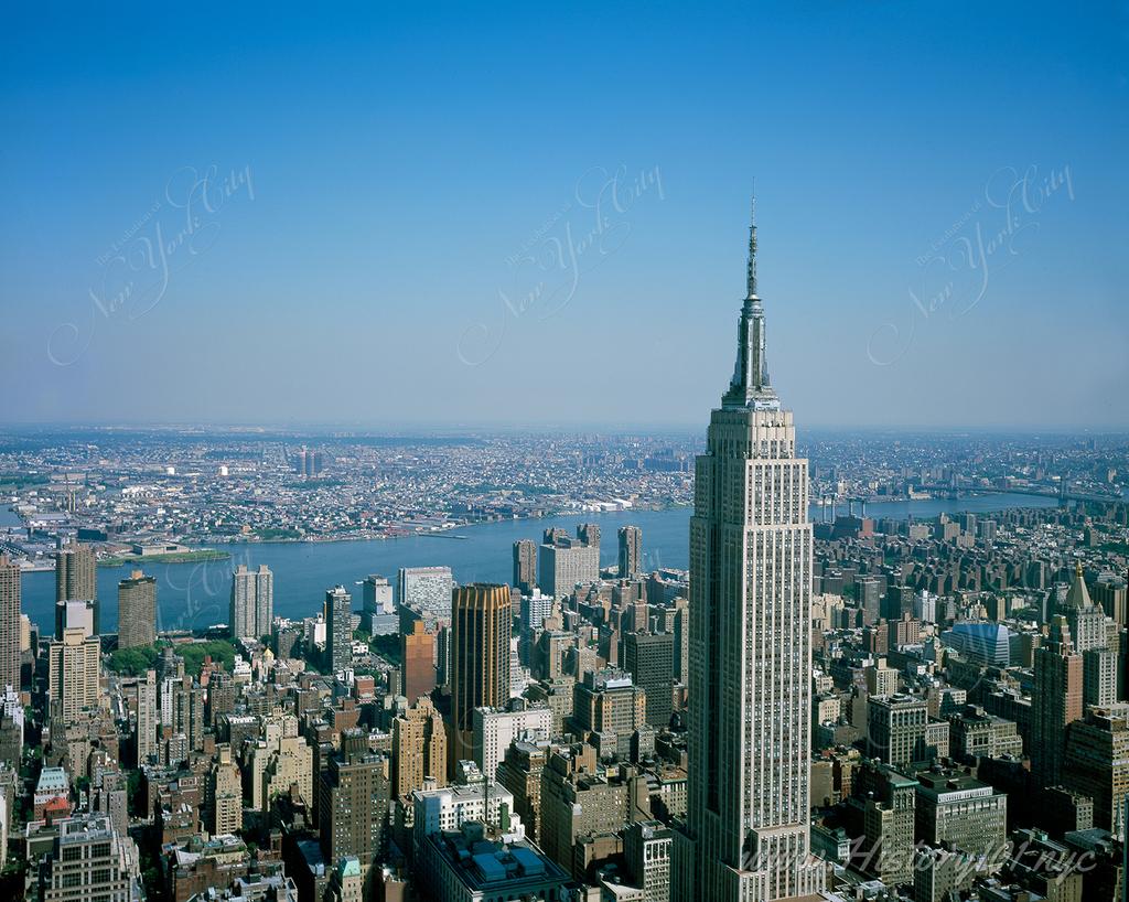 Aerial photograph of the Empire State Building and Manhattan's skyline with Queens and Brooklyn visible in the background.