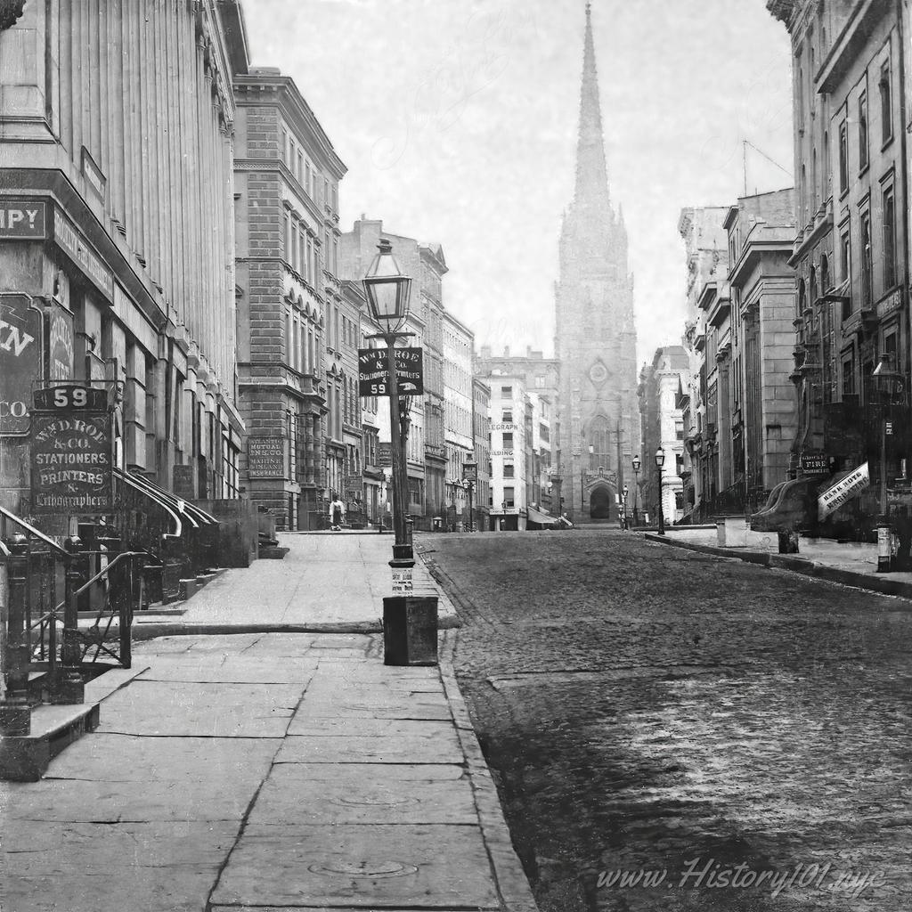 View of Wall Street with storefronts and Trinity Church in the distance. A sign of printer "Wm. D. Roe & Co." (at 59 Wall Street) is visible in the foreground.