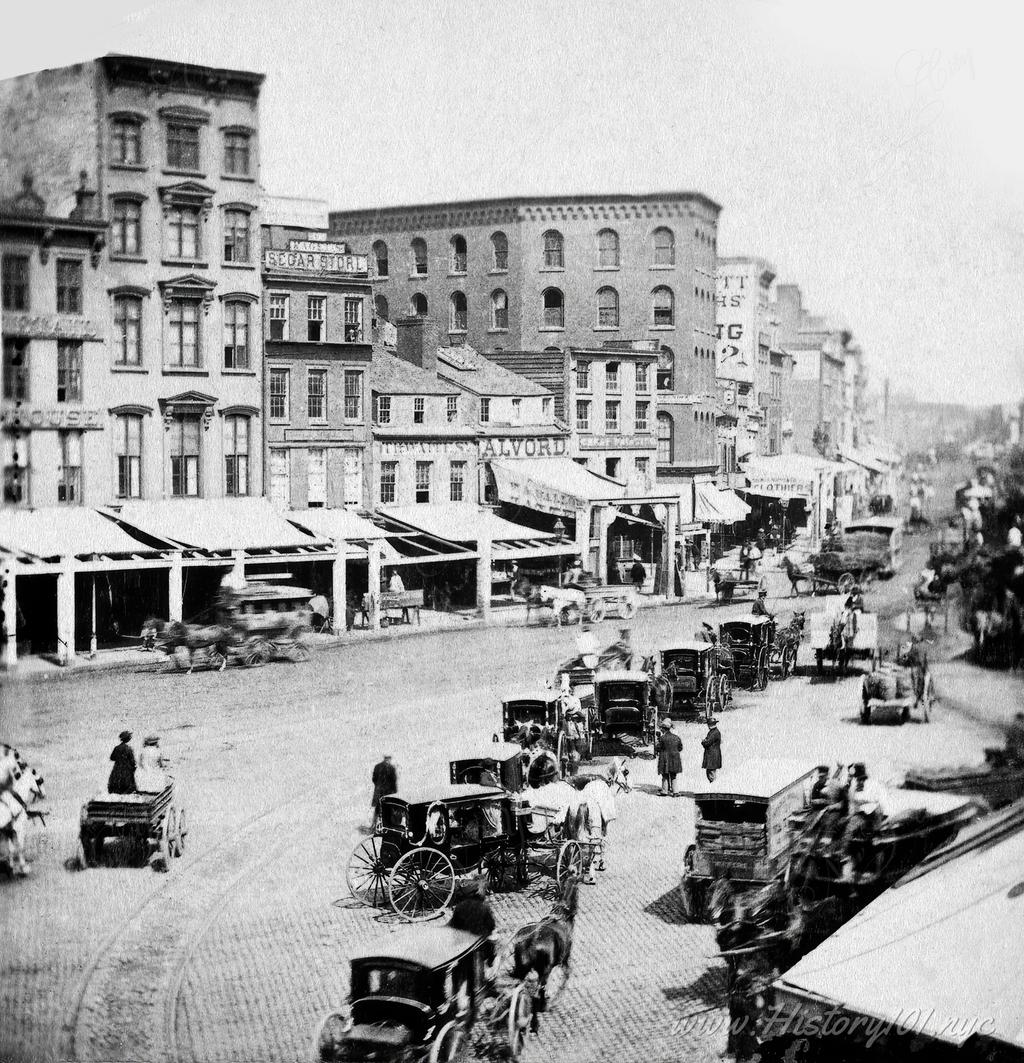 Explore a photograph of 1860s Chatham Square, NYC, showcasing bustling storefronts, pedestrians, and horse-drawn wagons in a vital commercial hub of Lower Manhattan