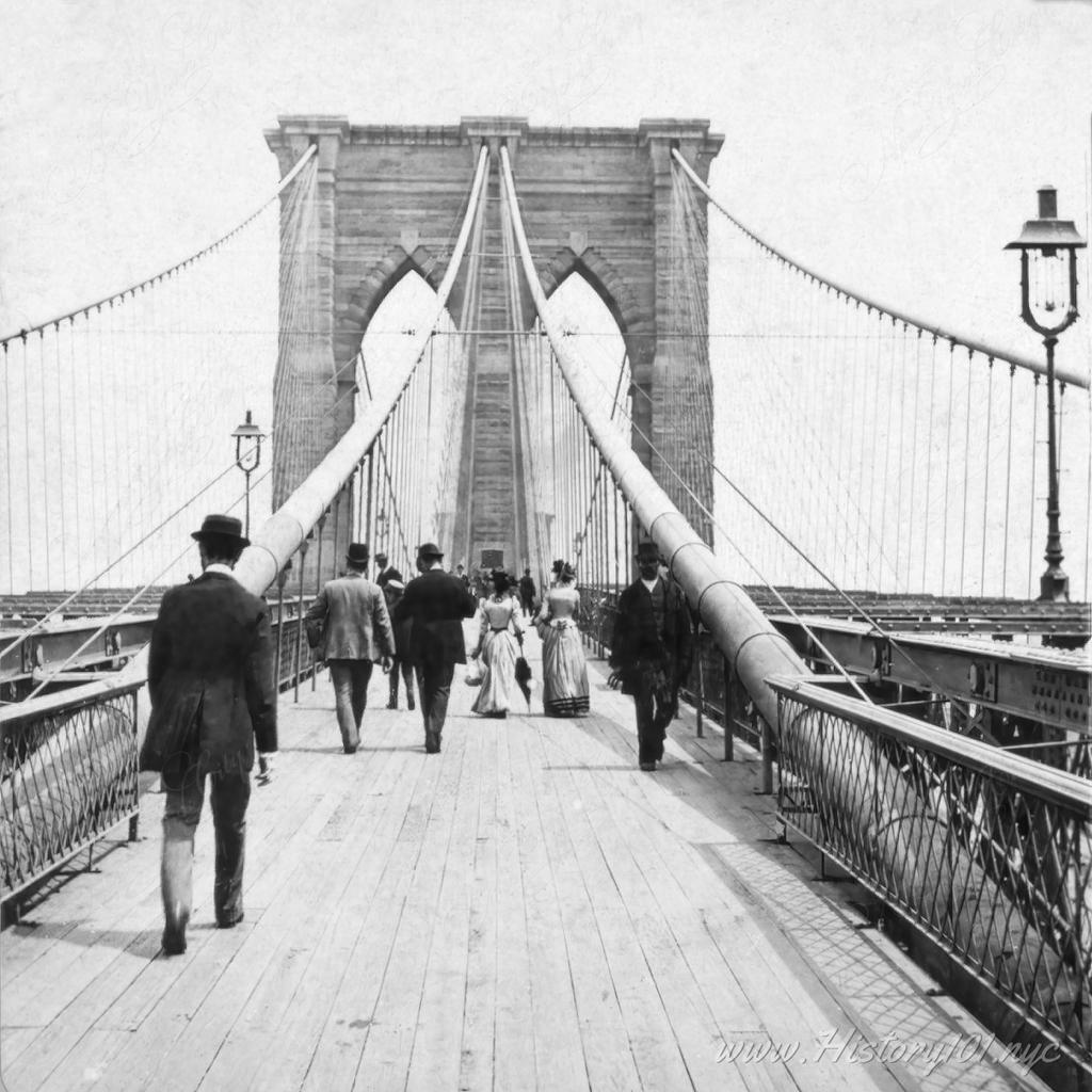 Photograph of pedestrians walking the Promenade of the Brooklyn Bridge, New York City.