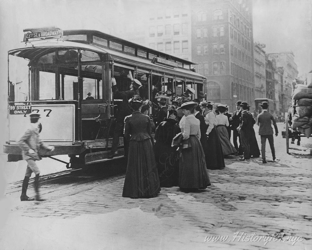 Photograph of commuters waiting to board a New York City streetcar, headed towards 23rd Street and Broadway.