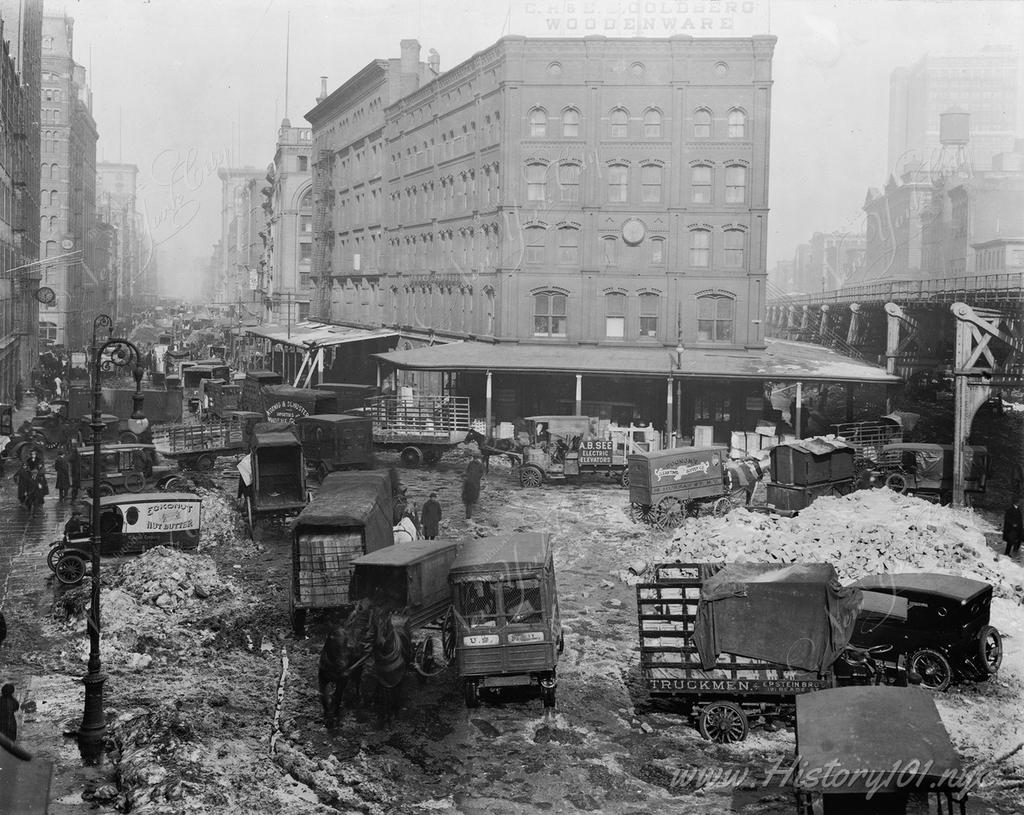 Photograph of Hudson Street, covered with snow and crowded with automobiles, trucks, wagons, and horses.