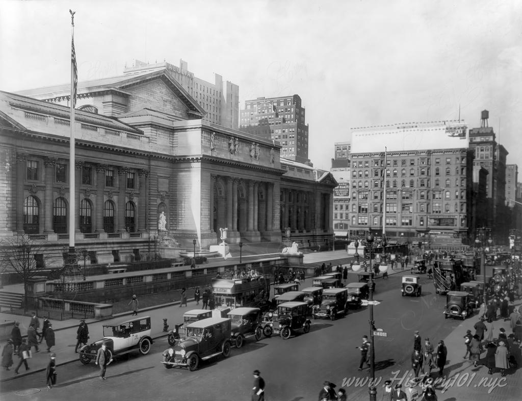 Photograph of a crowded street scene in front of The New York City Public Library at 5th Avenue & 40th Street.