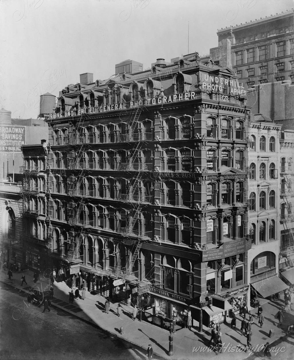 The corner of Broadway and Park Place, with pedestrians walking along street. A sign on top of the building reads "Irving Underhill General Photographer"
