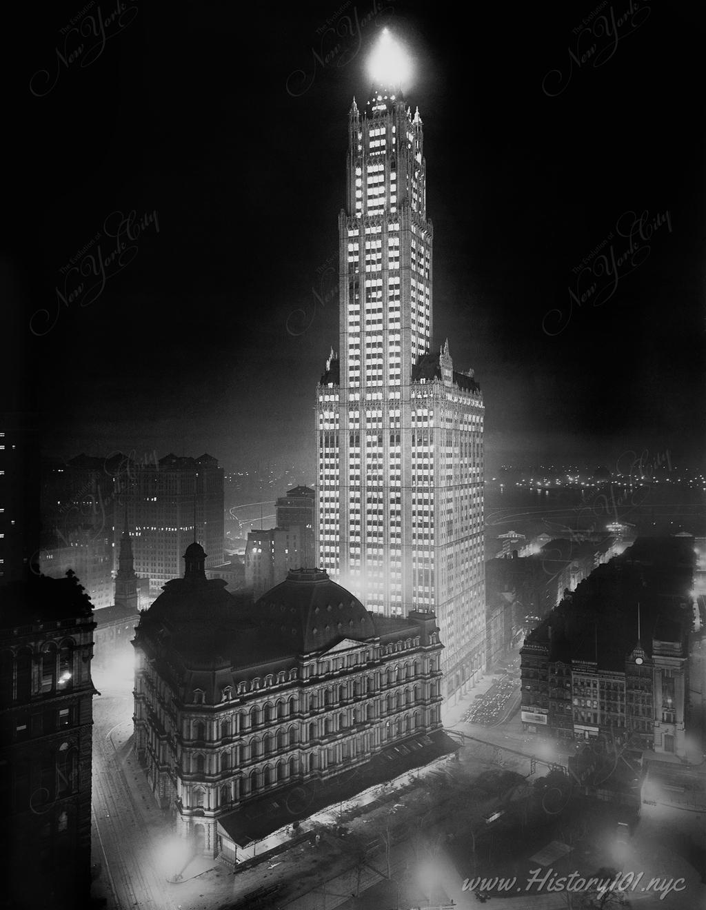 Photograph of the Woolworth Building and surrounding streets bathed in the artificial light of the city that never sleeps.