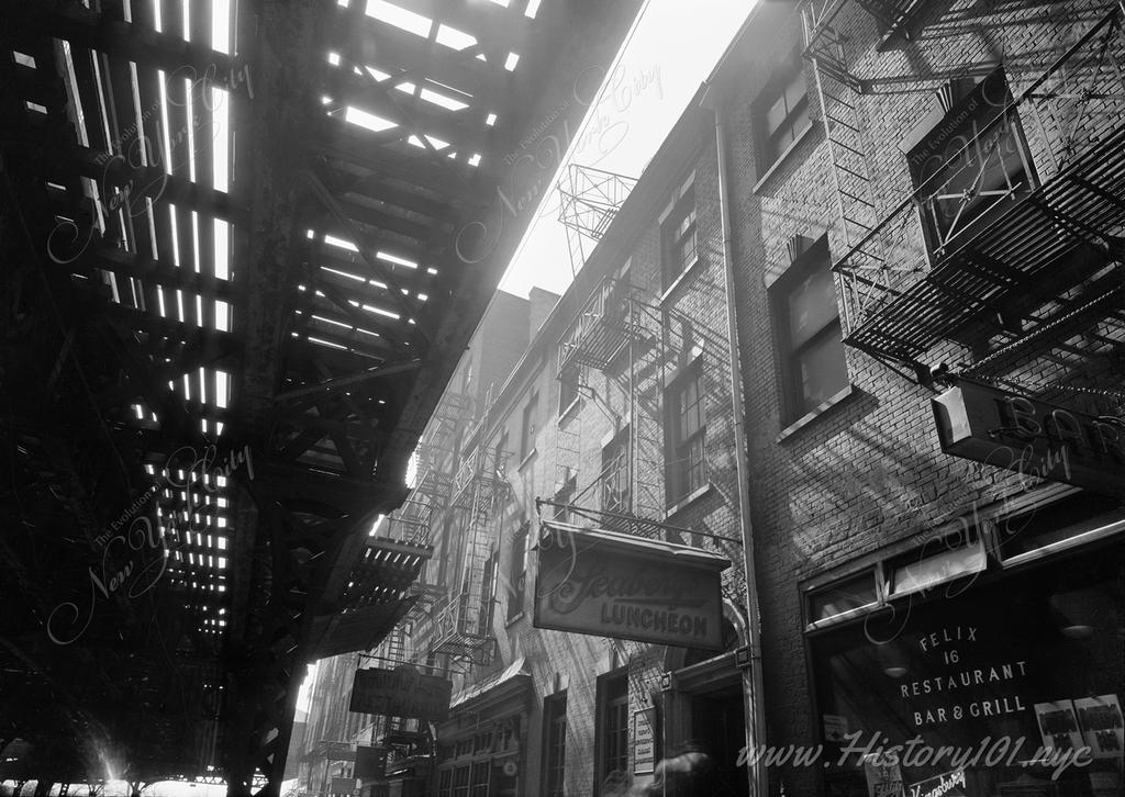 Exterior view of 16 Greenwich Street and adjoining buildings beneath the shadow of the elevated railroad  tracks.