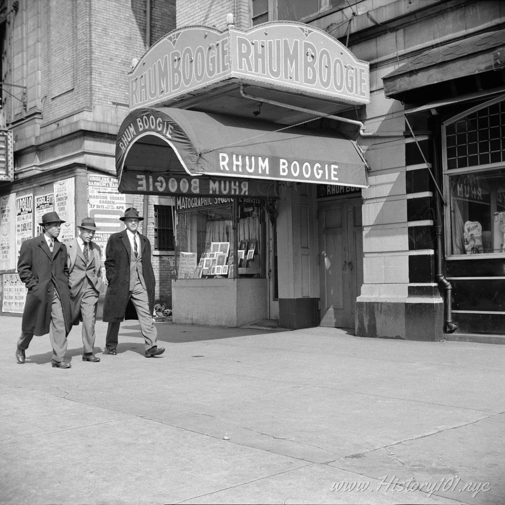 Photograph of three men walking down the street past on of Harlem's nightclubs.