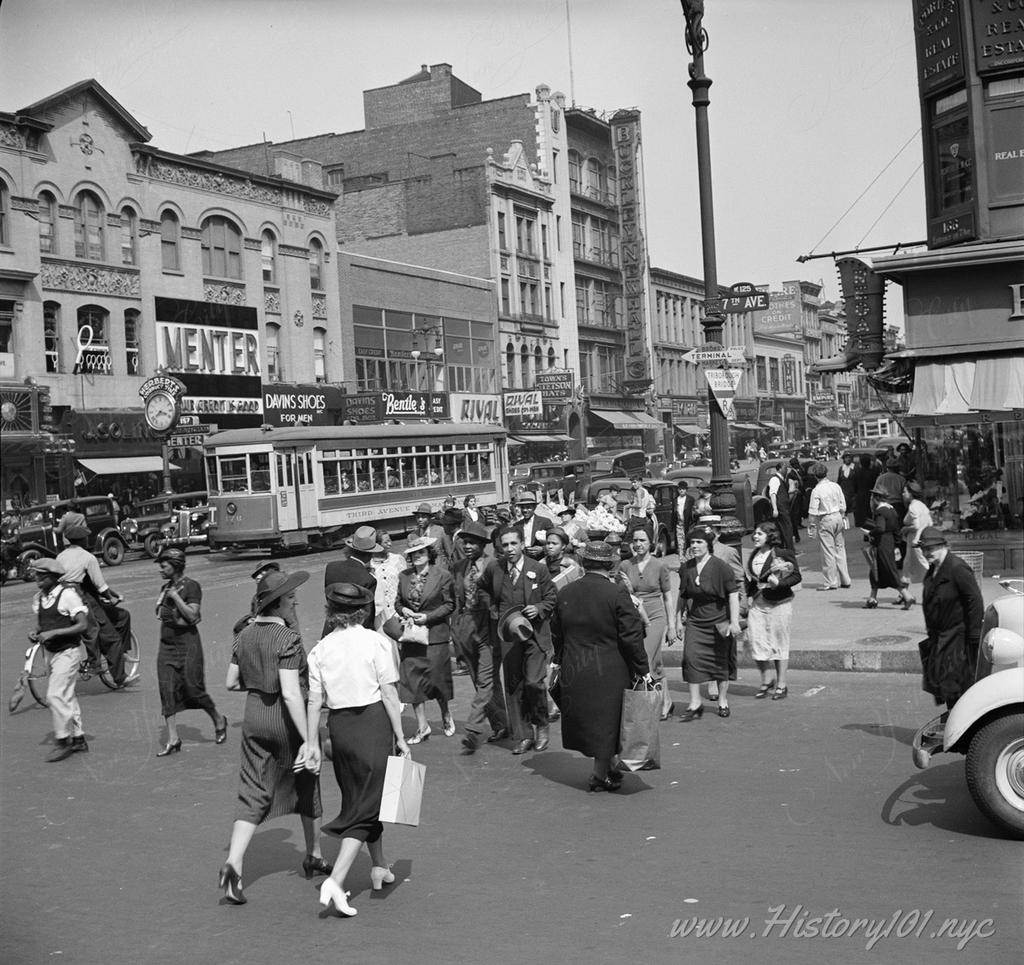 Photograph of traffic and pedestrians on the corner of 125th Street and 7th Avenue in Harlem.