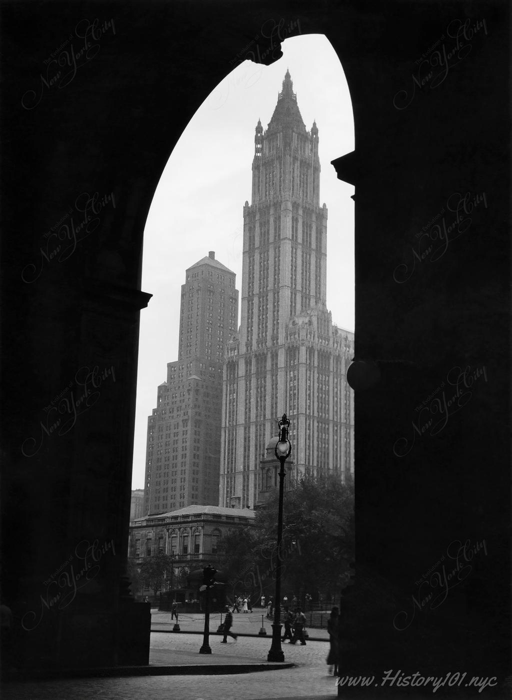Photograph shows the Woolworth Building framed by the interior of an adjacent building.