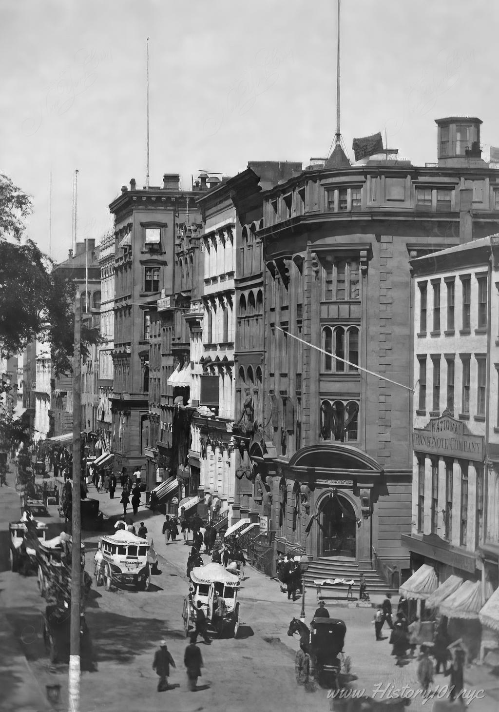 Photograph taken in 1865 shows the "National Bank of the Republic" (NBR) surrounded by other commercial buildings, pedestrians and traffic on Broadway.