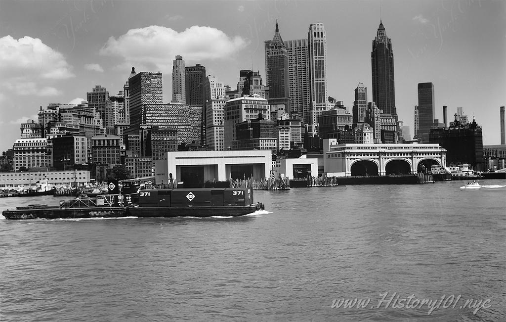 Panoramic photograph of the New York Harbor with tugboat  and lower Manhattan skyline.