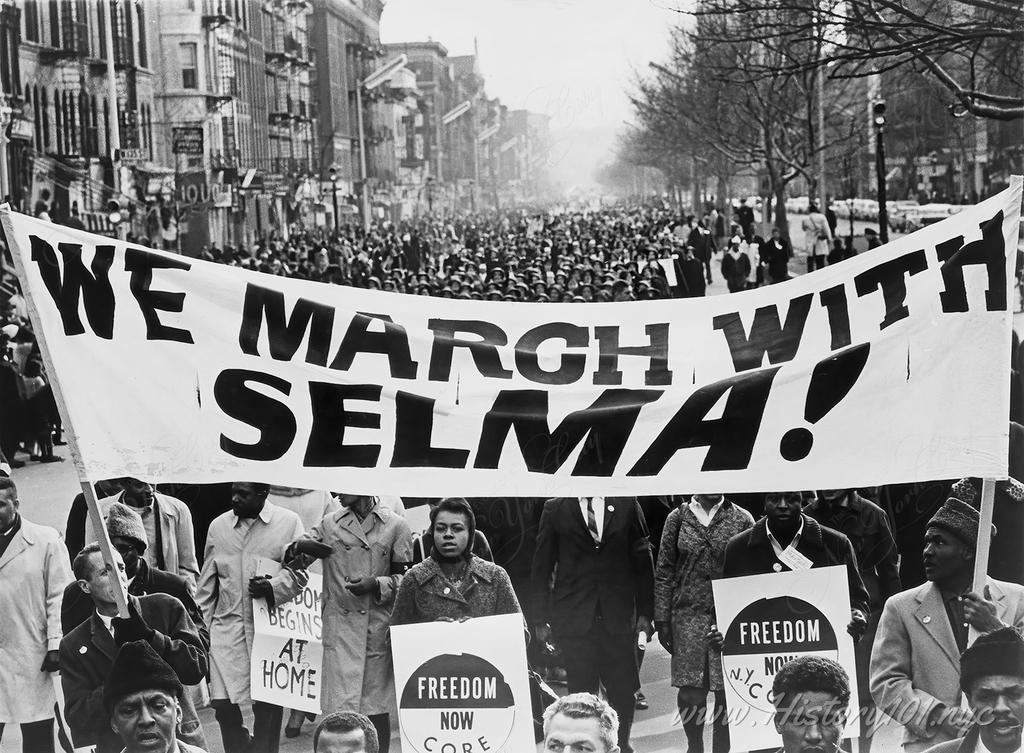 Photograph of marchers carrying banner and leading the way as 15,000 attend a solidarity march in Harlem.