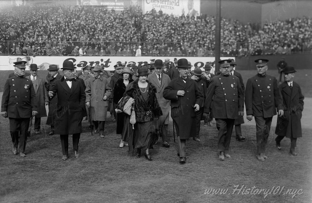 Photograph of Jacob Ruppert, Governor Al Smith & his wife escorted by police on the field of Yankee Stadium on opening day.