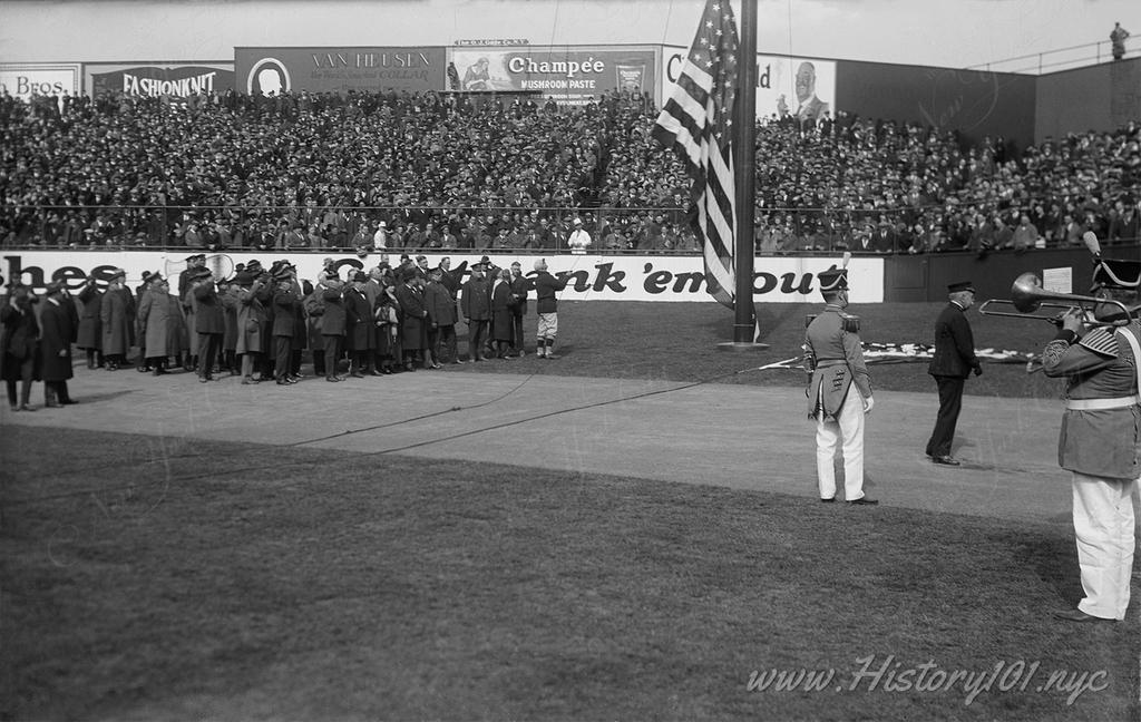 Photograph of police saluting the flag while the band plays on the field of Yankee Stadium on opening day.