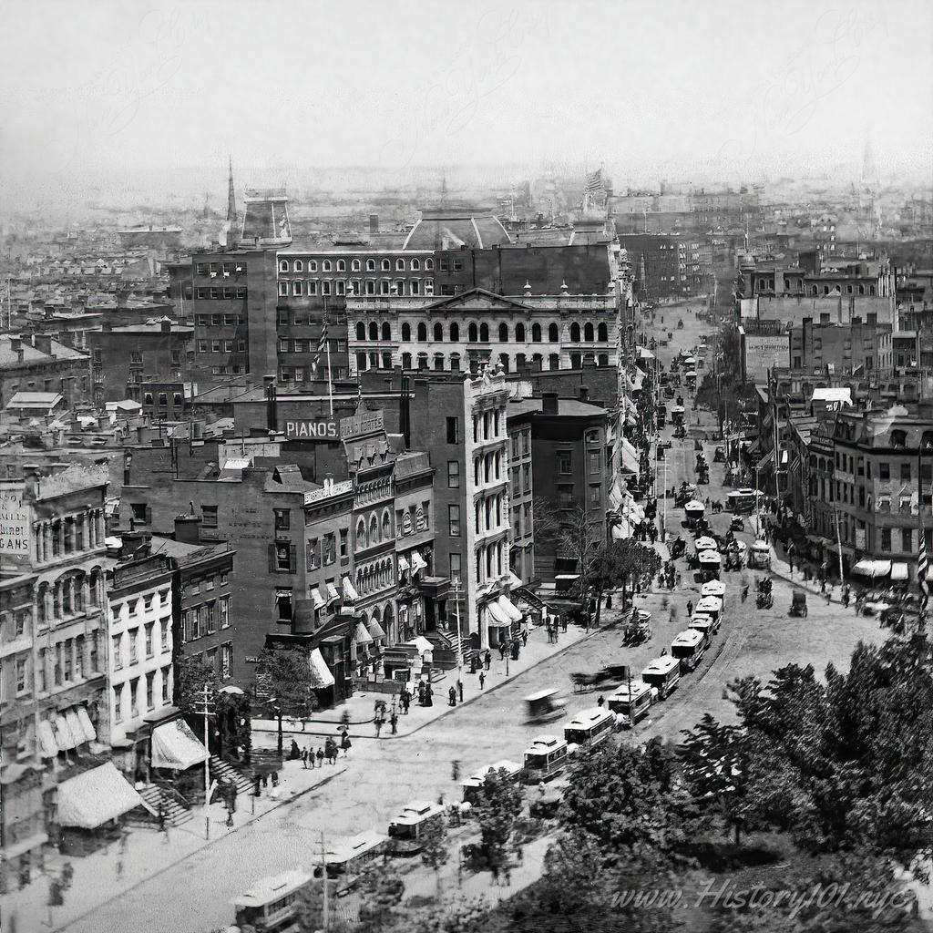 A photograph shows a famous intersection of downtown Manhattan, lined with trolleys and a vastly different urban landscape.