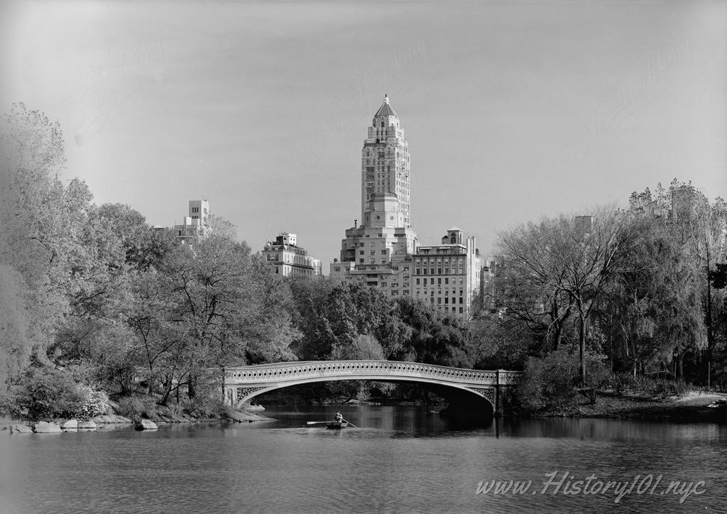 Photograph of Bow Bridge overlooking the Lake in Central Park with midtown  buildings in the background.