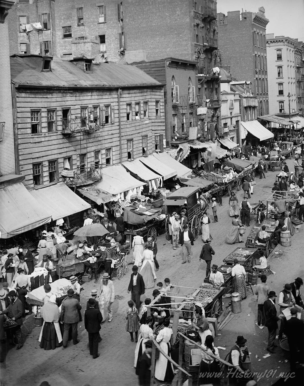 Photograph of a busy East side street lined with Jewish markets and filled with pedestrians.