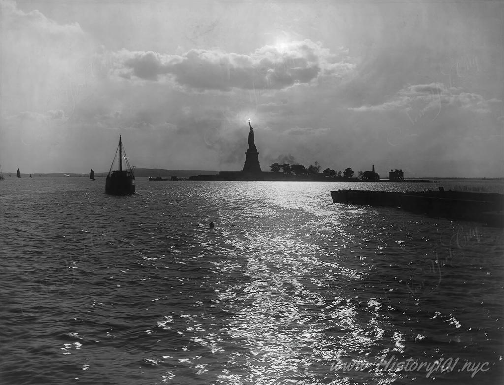 Photograph of the Statue of Liberty with her torch illuminating the sky over New York Harbor.