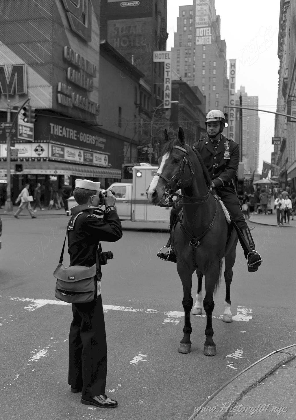 Explore the blend of military tradition and urban life in Times Square as a sailor photographs an NYPD officer on horseback during Fleet Week in New York City