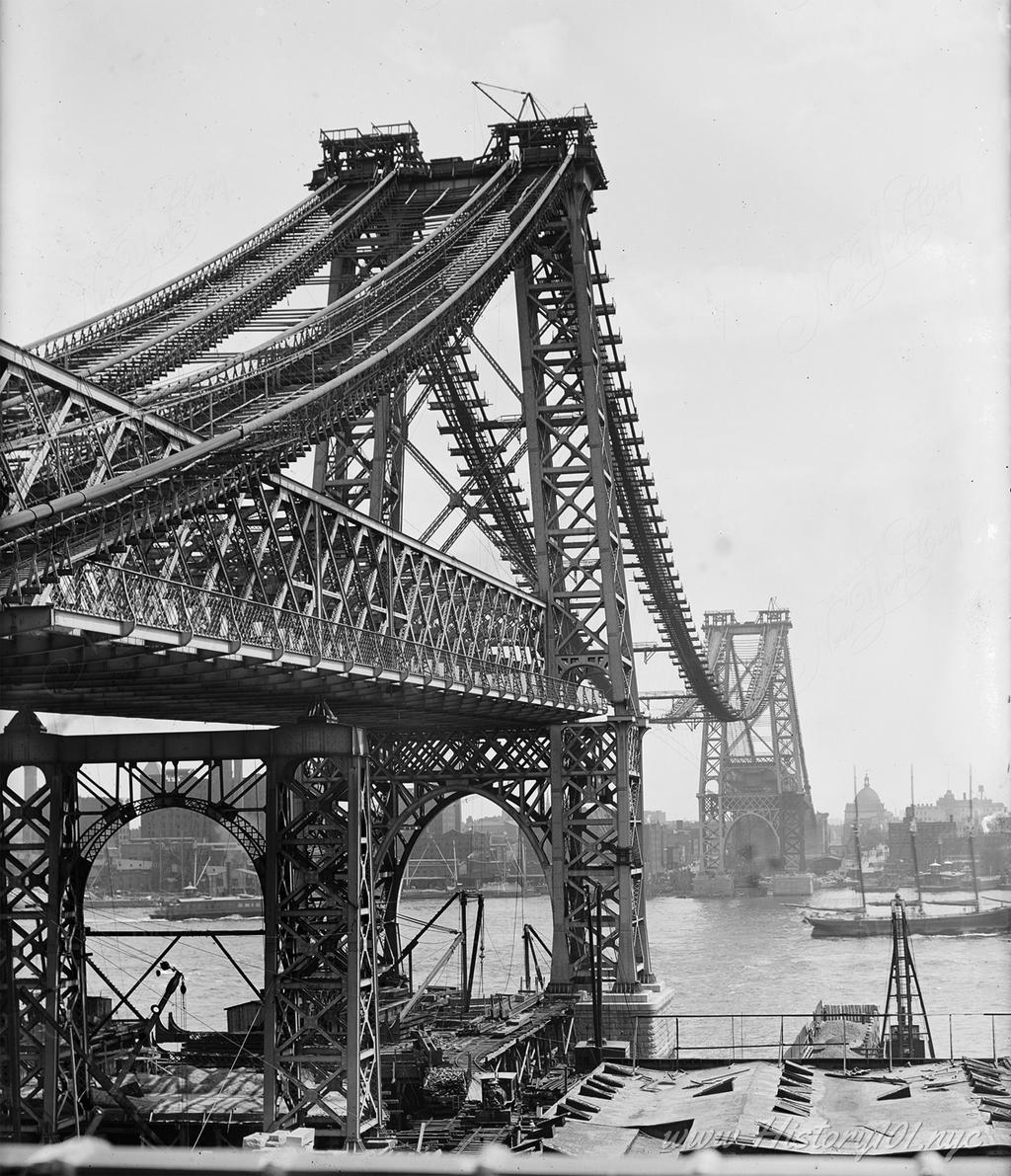 Photograph of a growing Williamsburg Bridge, spanning the East River and facing Brooklyn.