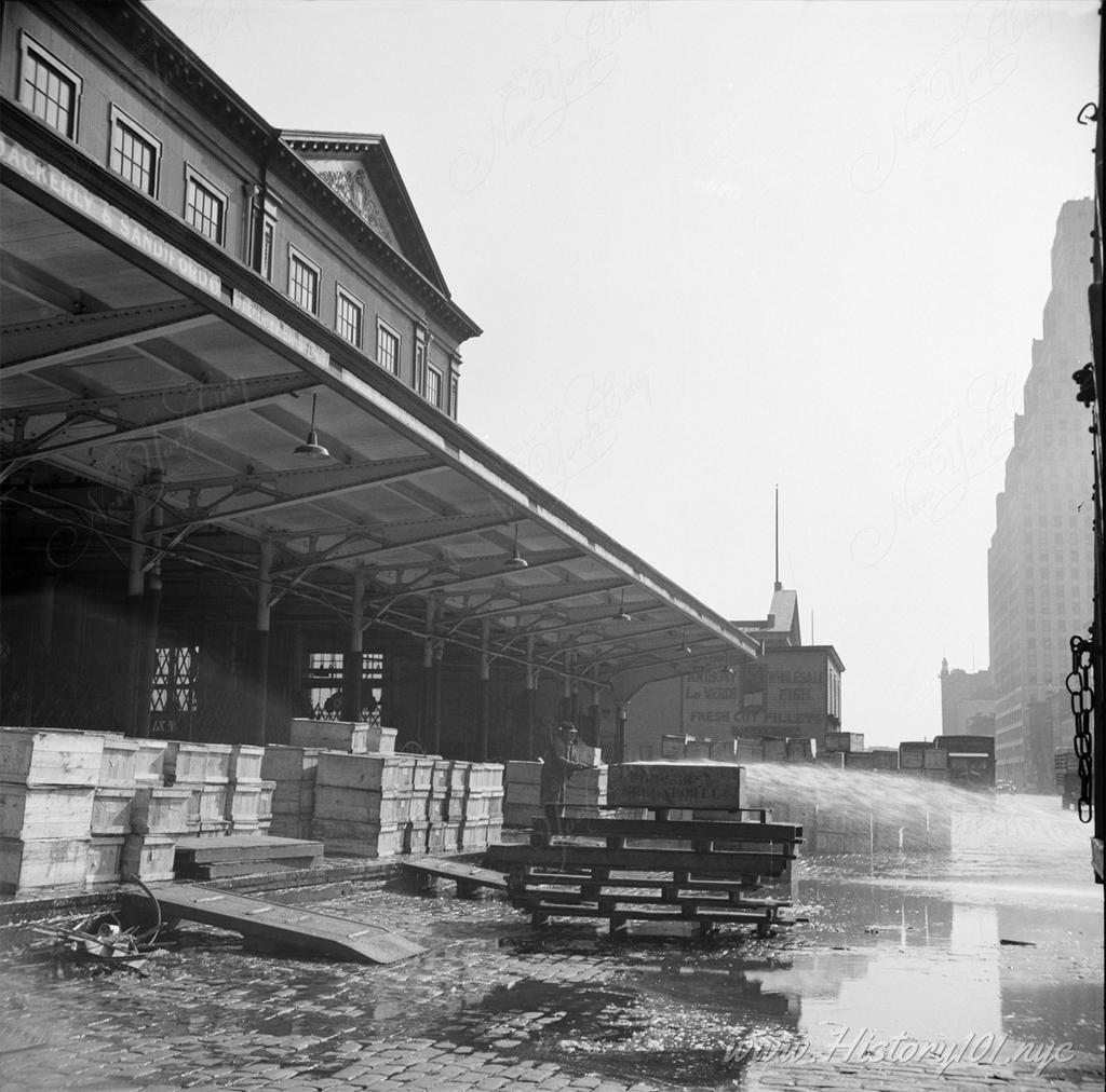 Evening photograph of a man hosing down the streets of Fulton Fish Market after hours.