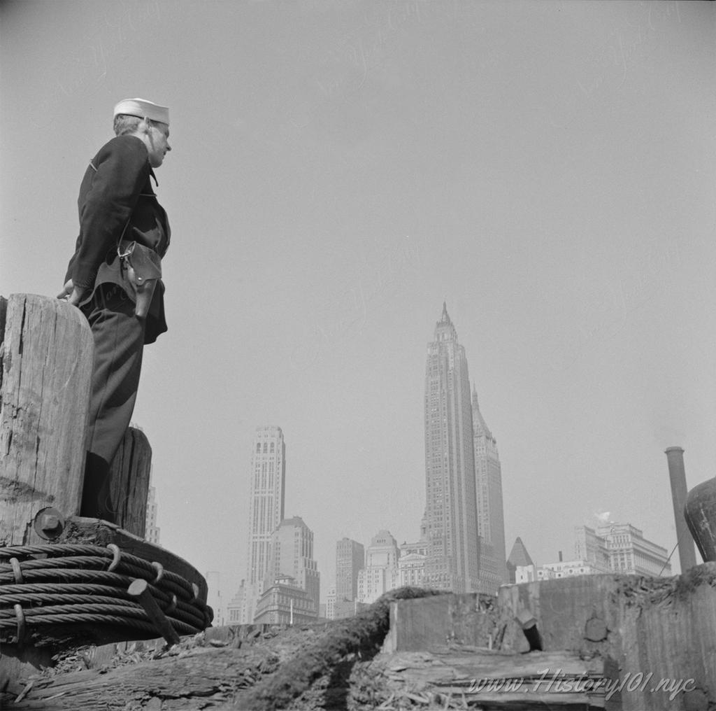 Photograph of a US Navy sailor standing on the pier at Fulton Fish Market in downtown Manhattan.