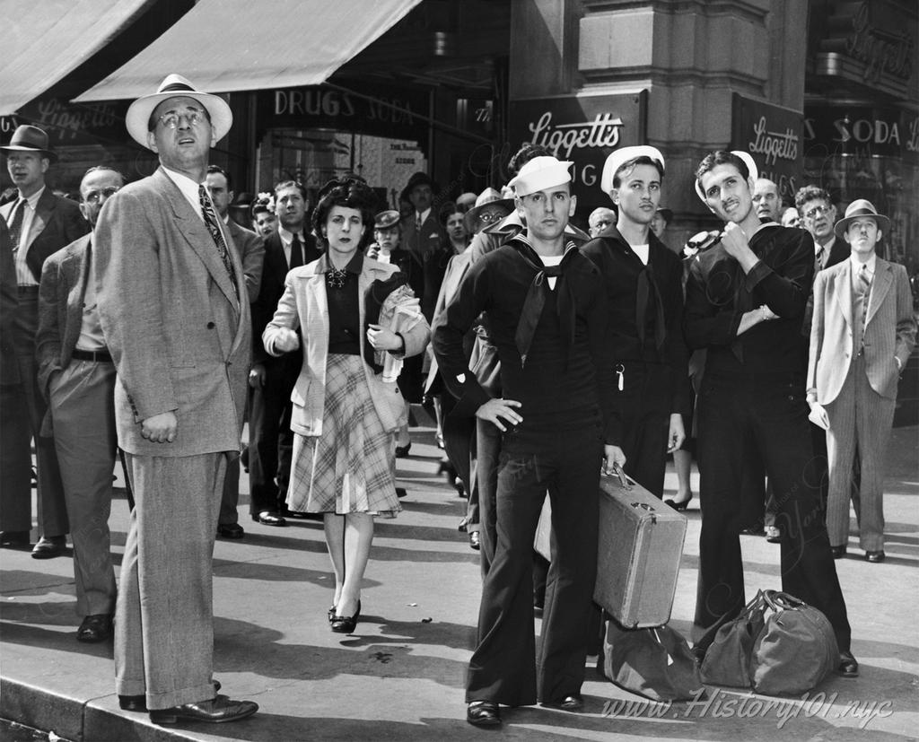 Photograph of sailors and civilians watching an electronic sign in Times Square for news of D-Day invasion.