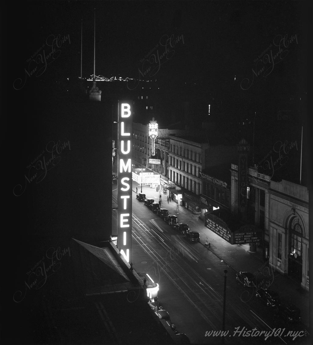 View of The Apollo Theater and 125th Street, illuminated by street signs at night.