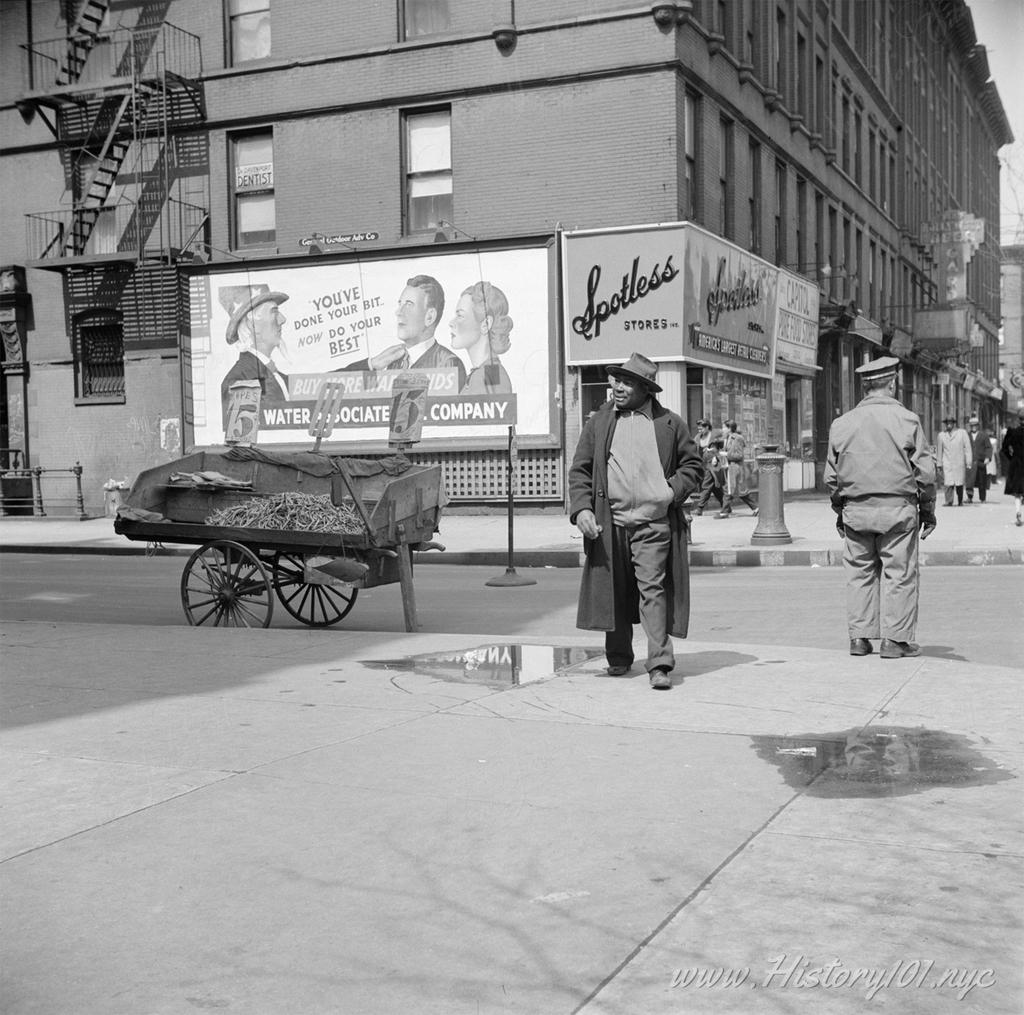 Photograph of a fruit stand vendor waiting on customers on a corner in Harlem.