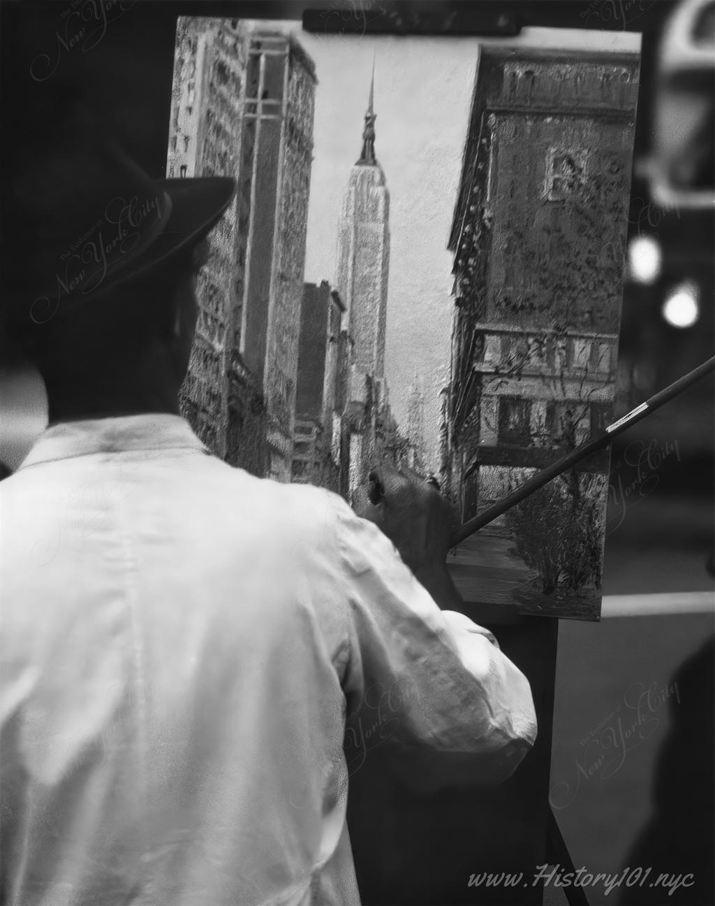 Photograph shows half-length portrait of an street artist working on a painting of Manhattan's urban landscape with the Empire State Building in the background.
