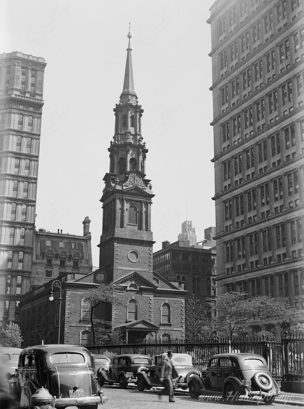 Photograph of cars parked along Broadway & Fulton Street in front of  St. Paul's Chapel in downtown Manhattan.
