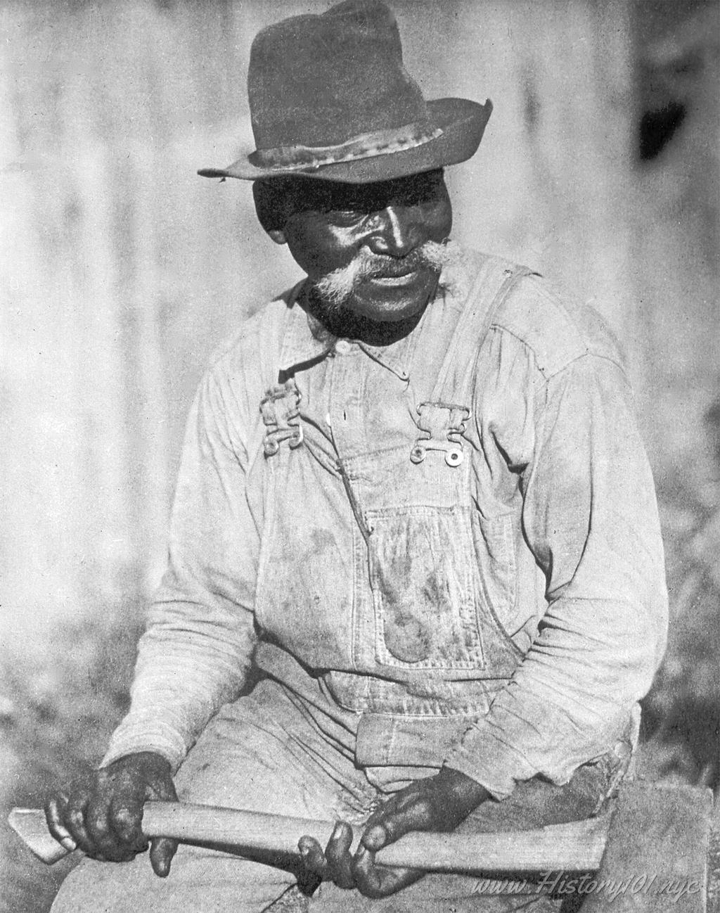 Photograph of a New York City Laborer posing for a portrait with an axe in his hands.