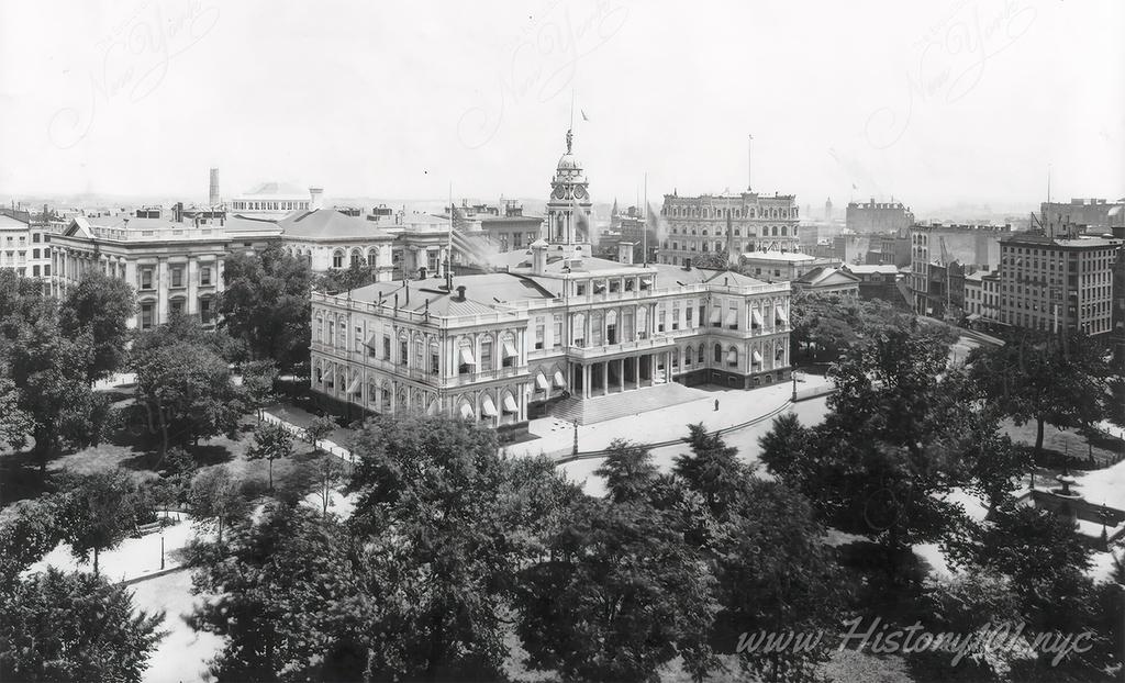 Aerial photograph of City Hall with its neighborhood buildings and surrounding park in downtown Manhattan.